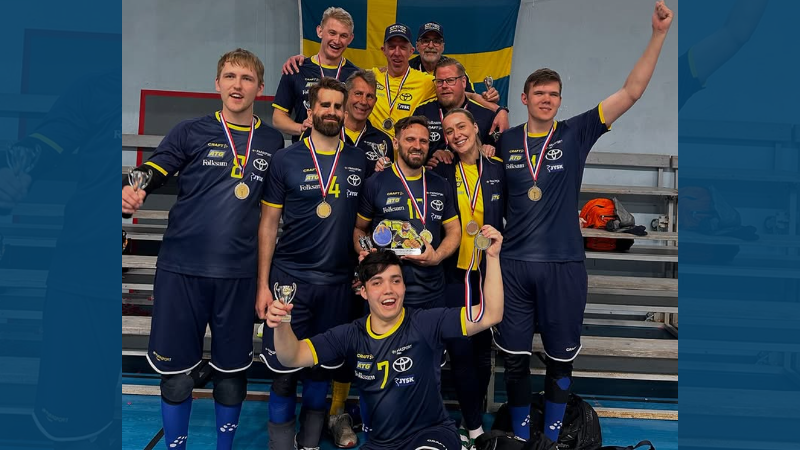  Grupp män i en mörkblå Sverige matchdräkt med varsin silvermedalj runt halsen. Goalball herrarna