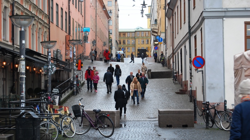 Foto kullerstensgata mellan äldre hus, gående