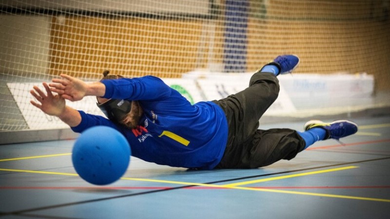En goalballspelare slänger sig raklång för att fånga en boll på väg.