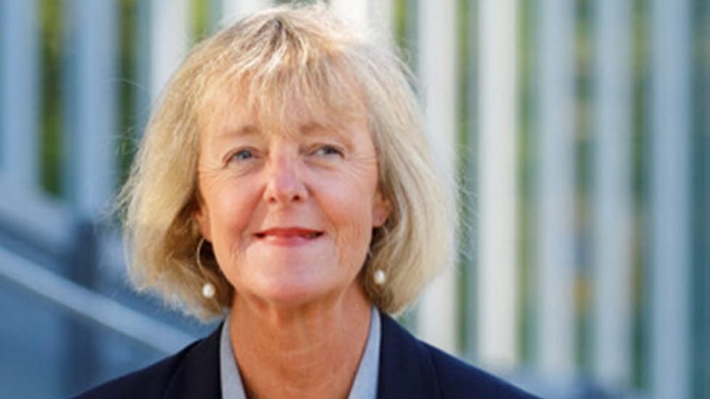 Blond, ljus äldre kvinna i page och mörkblå kavaj.