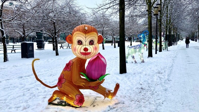 En lysande skulptur i form av en brun sittande apa, ser ut som på tecknad film. 1,5 meter hög, sitter i snön i Kungsträdgården.