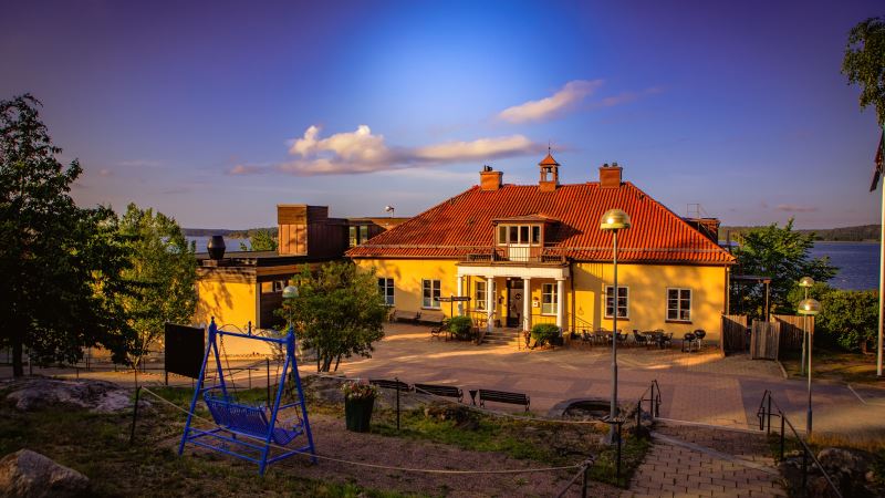 Äldre gul herrgårdsbyggnad med trädgård i skärgården.