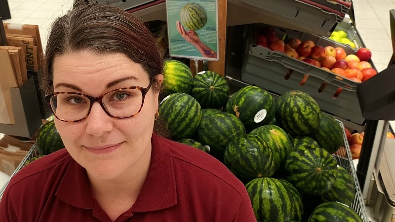 Lia Daun, en kvinna i yngre medelåldern med brunt hår ser upp mot kameran framför en stor korg med vattenmeloner.
