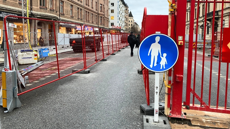 Gångpassage på Götgatans körbana. Röda stängsel skyddar mot byggarbeten på båda sidor av gången