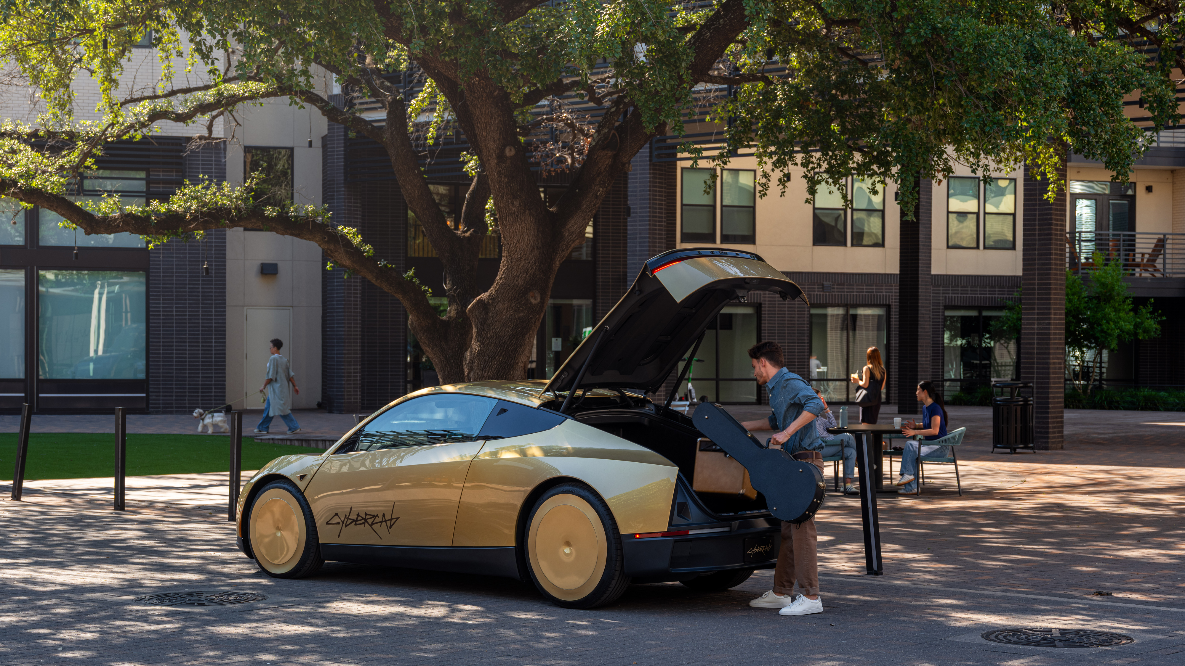 En guldfärgad, futuristisk bil med slanka linjer står parkerad under ett träd. En man lastar in ett gitarrfodral genom bilens uppfällda dörr.