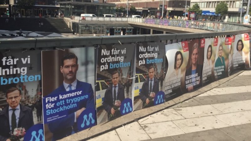 Valaffischer prydda med porträtt och korta budskap hänger tätt längs ett staket över Serges torg.