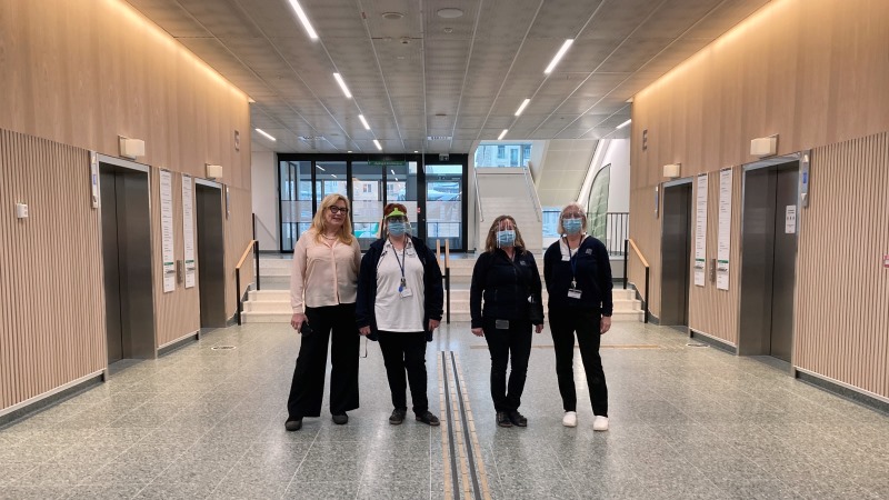 Fyra kvinnor står bredvid varann på S.t Eriks ögonsjukhus. På vardera sidorna flera hissar.