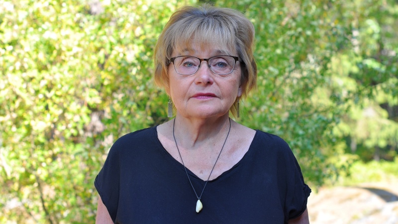 En blond äldre kvinna med glasögon.