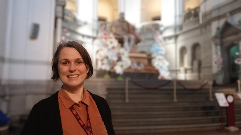 Wenke Rundberg, en vit medelålders kvinna med mörkbrunt uppsatt hår står i den stora hallen på Nordiska muséet.