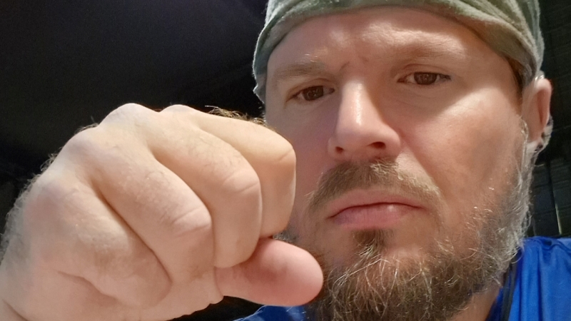 Närbild ansikte vit man, håller en knuten näve framför sig