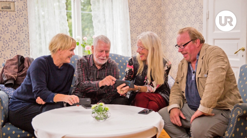 Fyra äldre personer sitter i en soffa runt ett bord, två kvinnor och två män.