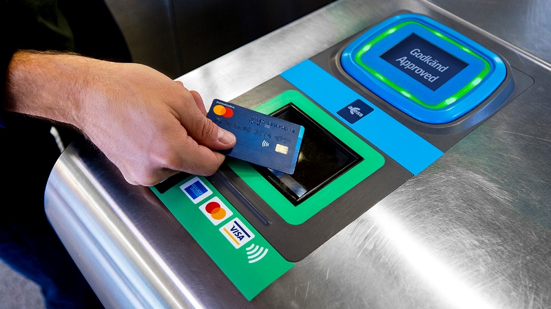 Hand som lägger betalkort på biljettläsare i tunnelbanespärr.  