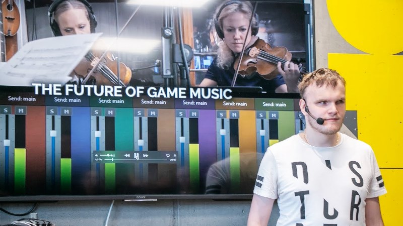 Kille med kort ljus hår, vit T-shirt står framför en filmduk med datorgrafik på.