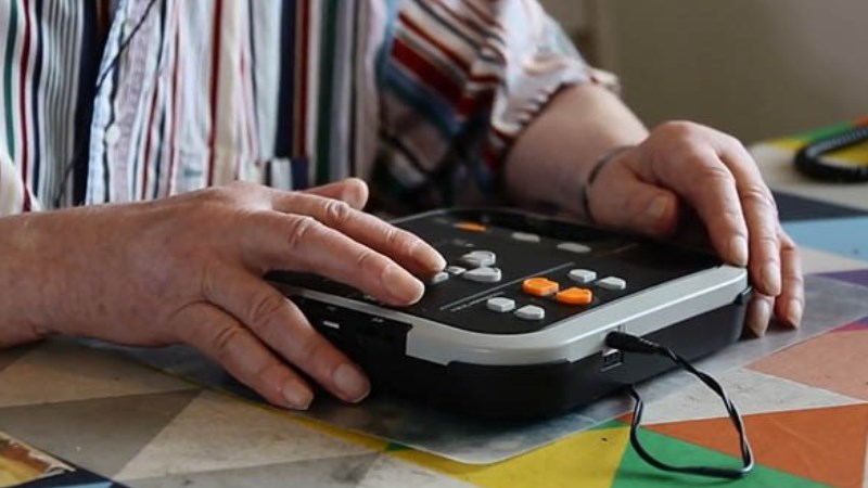 Närbild, händer av äldre man knappar på en Daisyspelare