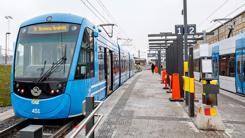 Blå spårvagn vid plattform.