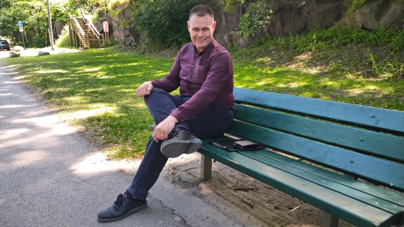 Man sitter på en träbänk i en park