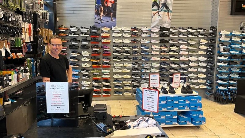 En vit medelålders man står i en svart t-shirt i en skobutik.