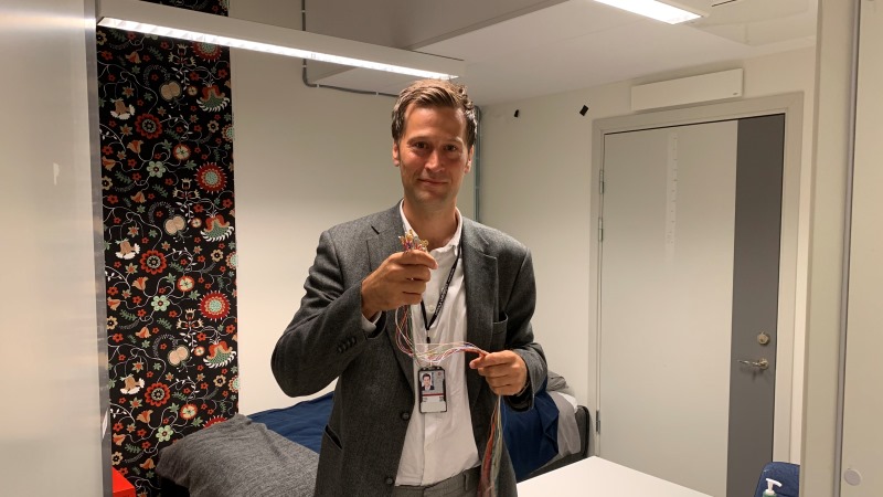 Ljus man i kavaj håller i elektrodsladdar för sömnforskning