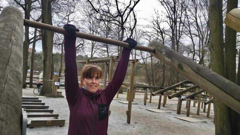 Kvinna i lila träningströja på utegym